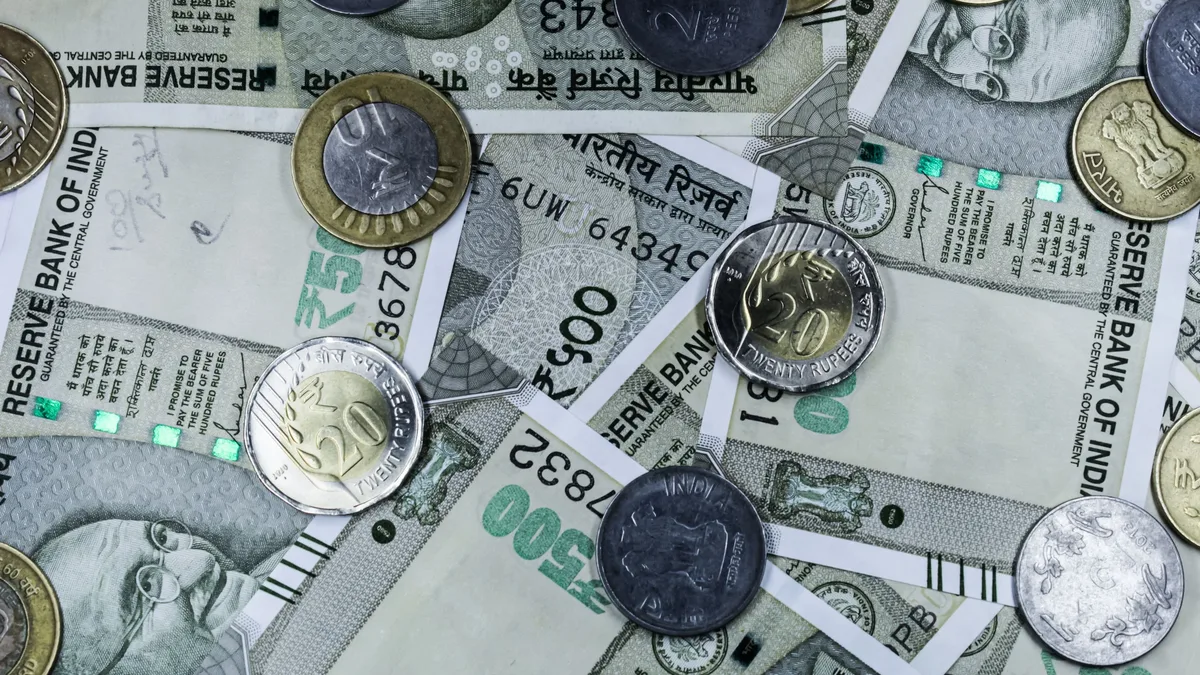 A collection of Indian currency, including banknotes and coins, with the Reserve Bank of India logo visible on the banknotes.