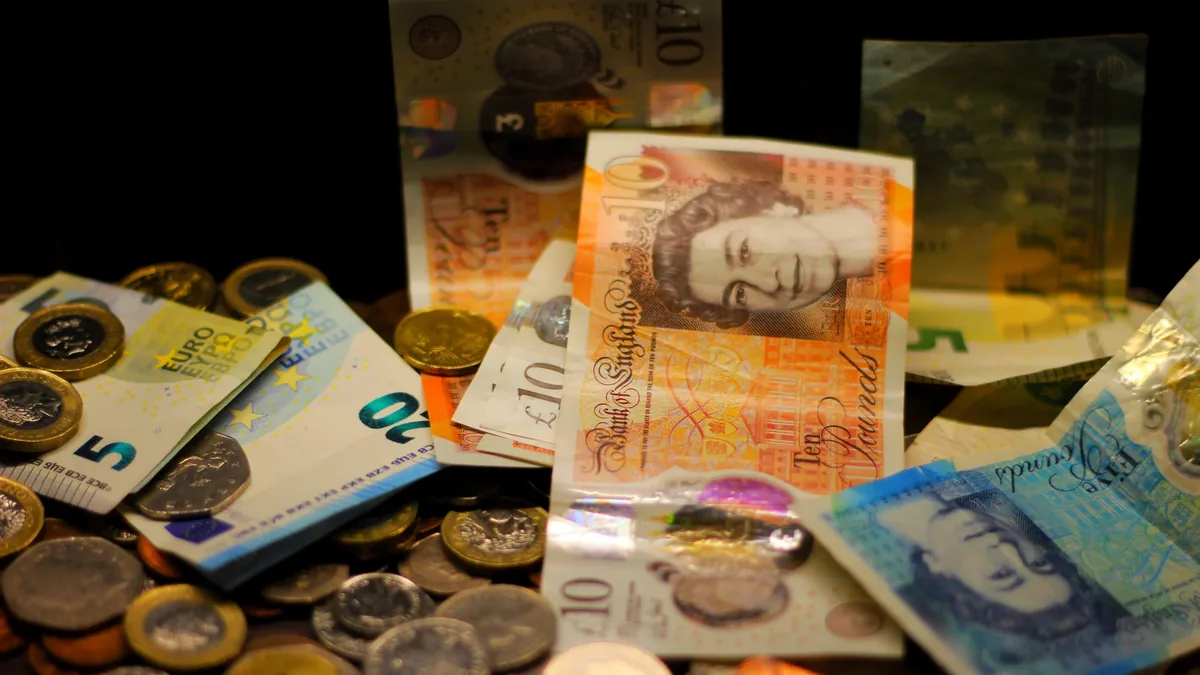 A collection of British banknotes and coins scattered on a surface.